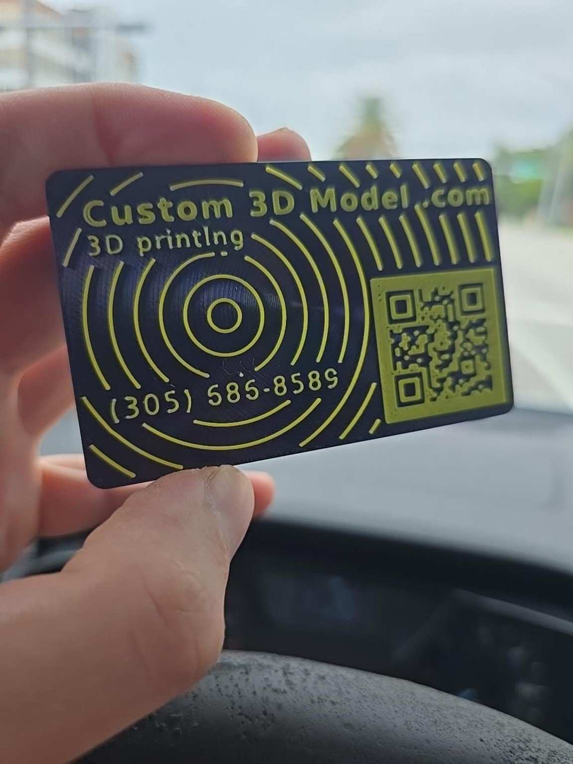 An actual 3D printed business card being held between fingers to show its size
